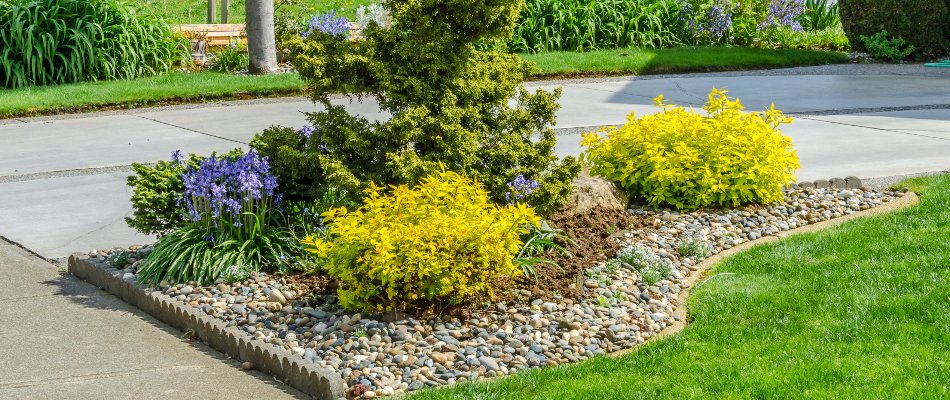 Landscape bed of colorful flowers and decorative rock installed by Storm in Eagle Lake, MN.